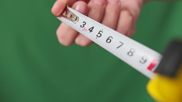 Hands mechanics craftsman pull measuring tape on grey isolated background. Measuring with yellow tape measure, working home service job. Close up.