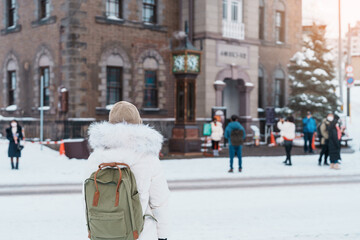 Woman tourist Visiting in Otaru, Traveler in Sweater sightseeing Otaru Music Box Museum with Snow in winter season. landmark and popular for attractions in Hokkaido, Japan. Travel and Vacation concept