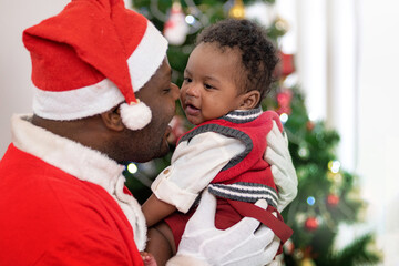 African Santa father holding and playing with his son, Christmas time together