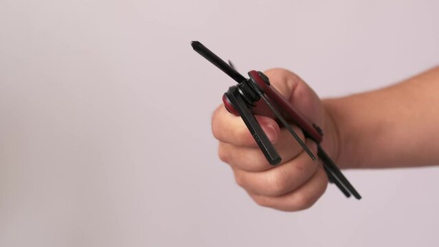 Multipurpose bike tool, red key hex in man hand, isolated on white background, close up. Portable work tools for repair.
