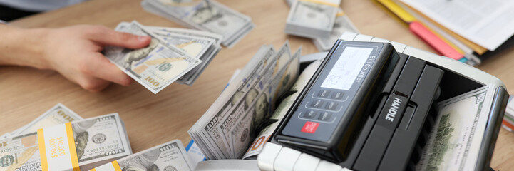 Woman uses bill counter to count money after profitable deal