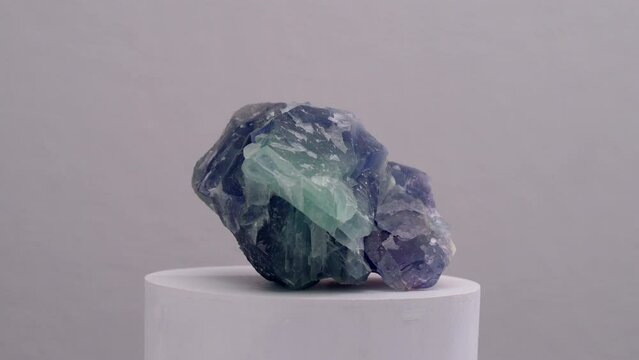 Fluorite Rainbow Quartz Mineral Crystal green purple stone for meditation healing therapy or decoration rotating shot over white surface on light background