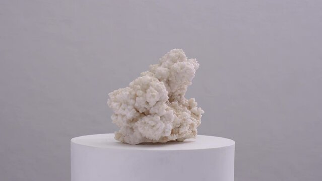 Aragonite White Quartz Mineral Stone Rock Gemestone semi precious spining on white concrete pedestal exhibition decoration piece concept