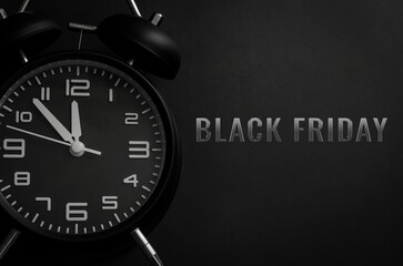 Black alarm clock with word Black Friday on black background for Black Friday shopping reminder concept.