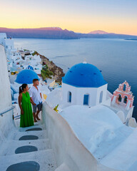 A couple of men and woman on vacation in Greece visited the village of Oia Santorini during sunset, a mature couple on a luxury holiday - obrazy, fototapety, plakaty