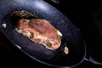 Chef cooking juicy beef meat on frying pan with rosemary and garlic, uses kitchen utensils. Process of roasted steak cooking.