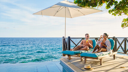 Curacao, a couple of men and woman mid age relaxing by the swimming pool during vacation, man and women by the pool in Curacao during holiday at a tropical island luxury vacation in the Caribbean