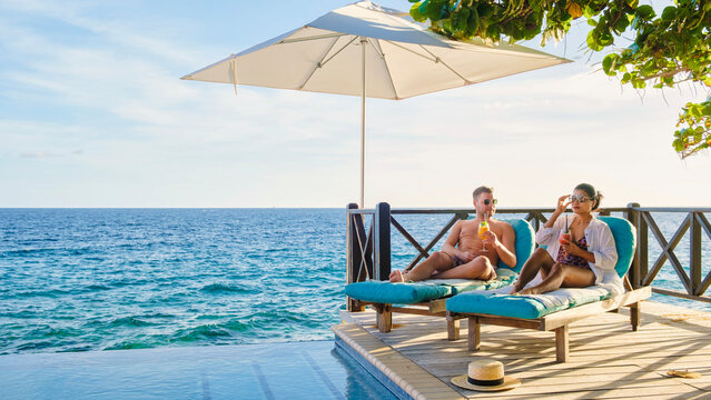 Curacao, a couple of men and woman mid age relaxing by the swimming pool during vacation, man and women by the pool in Curacao during holiday at a tropical island luxury vacation in the Caribbean
