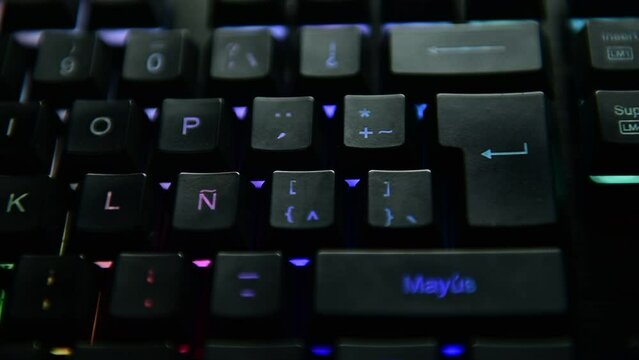 Man's hand pressing the ENTER key on a multicolor backlit black computer keyboard. selective focus.