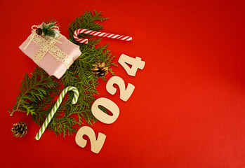 Christmas frame with a branches of thuja and gifts on a red background. Winter holidays. Space for...