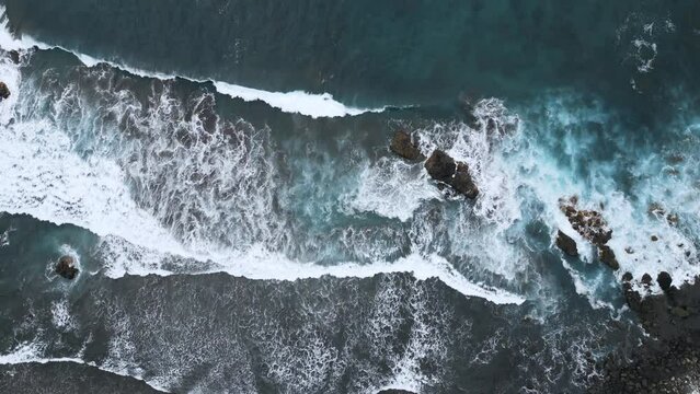 4k aerial view of a black sand beach with breaking waves in Tenerife