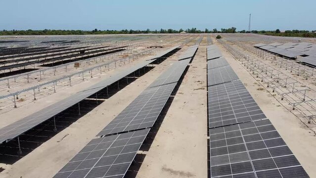 Aerial sliding left view over dirty and dusty bifacial solar panels at Jambur solar generation project site under construction - Gambia