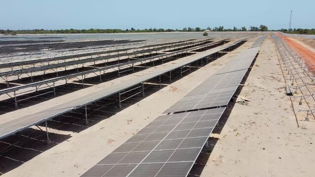 Aerial close-up pan right view over dirty dusty bifacial solar panels at Jambur solar PV project site