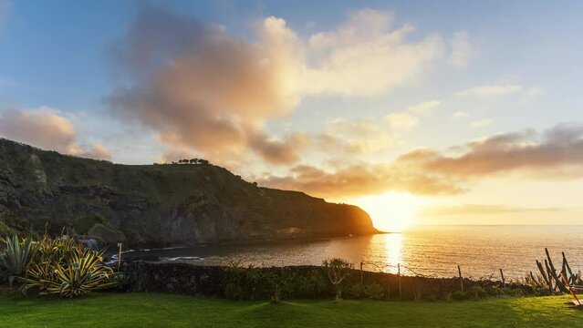 Time lapse of picturesque sunset in Sao Miguel island, Azores - Portugal. View of the coastline, warm traveling clouds, setting sun.
