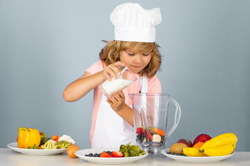 Portrait of chef child in cook hat make milk shake smoothie. Cooking at home, kid boy preparing food from vegetable and fruits. Healthy eating.