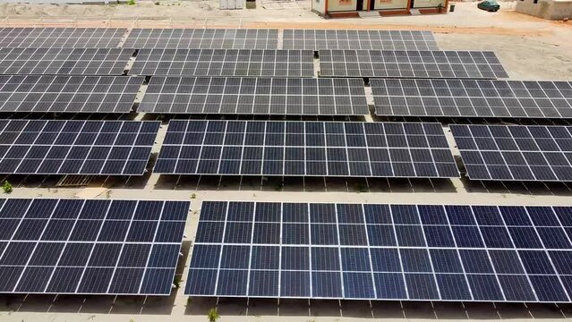 Aerial low sliding left showing dusty and clean bifacial solar panel arrays at NAWEC TBEA Jambur PV power plant under construction