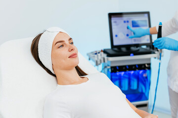 Young woman is relaxing getting vaccum facial hydro peeling procedure in beauty salon. Hardware...