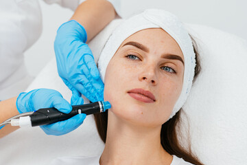Young woman is relaxing getting vaccum facial hydro peeling procedure in beauty salon. Hardware...