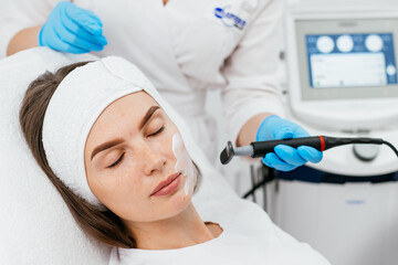 Close-up of a young woman's face during microcurrent therapy. Procedure for electrical stimulation of the face, rejuvenation, anti-wrinkle. The concept of youth and modern cosmetology technologies.
