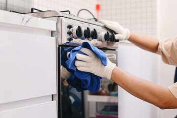 Close up of hand cleaning and wiping kitchen stove with fiber cloth