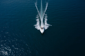 People on a white boat in motion aerial view. High speed white boat fast movement top view.