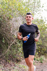 Fototapeta premium vertical portrait of a man practicing trail running in the forest, concept of sport in nature and healthy lifestyle, copy space for text