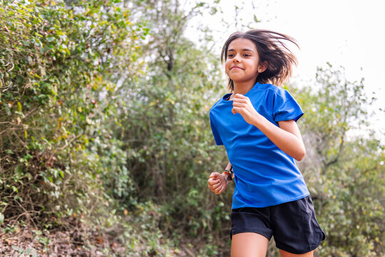 kid practicing trail running in the forest, concept of sport in nature and healthy lifestyle for children, copy space for text
