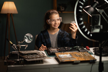 Fototapeta na wymiar Digital World with DIY Magic. Young blogger wields her smartphone and ring light to share her tech repair expertise, inspiring a new generation of electronics enthusiasts one video at a time.