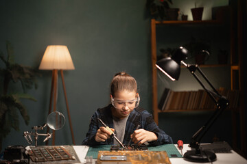Girl spends time repairing the motherboard, soldering electronics, improving, child passionate electricity