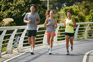 three young asian adults running jogging outdoors
