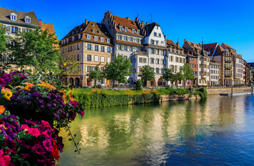 Fototapeta na wymiar Ornate traditional half timbered houses with steep roofs above the Ill River with blooming flowers, the historic center of Strasbourg, Alsace, France