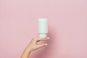 Bottle of pills or vitamins in woman's hand. Product branding mockup.