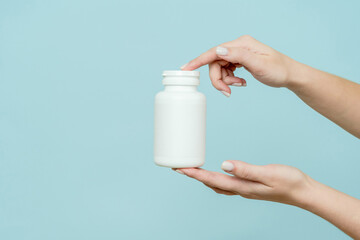 Woman's hand holds white plastic tube. Bottle for pill, capsule or supplement. Product branding...