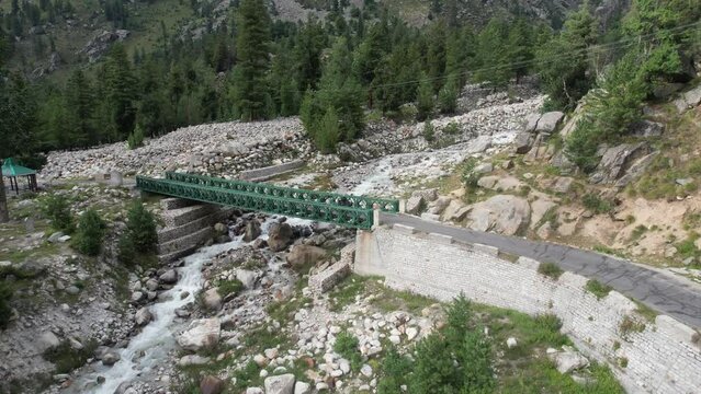 Aerial view of a steel bridge over a rocky mountain stream in the Himalayas, India