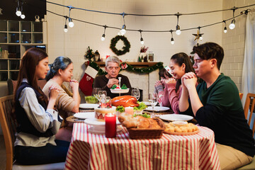 Asian happy family celebration on christmas day, sitting and closed eyes keep hands folding in...