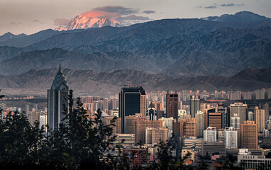 The sunset view of the urban skyline of Urumqi in Xinjiang and the Bogeda Peak in the distance