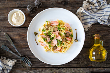 Tagliatelle with salmon and mayonnaise on wooden table
