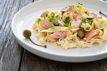Tagliatelle with salmon and mayonnaise on wooden table
