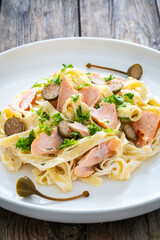 Tagliatelle with salmon and mayonnaise on wooden table
