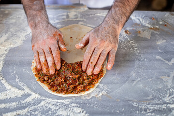 Preparing and baking lahmacun . Hands of a male making meat pizza. 