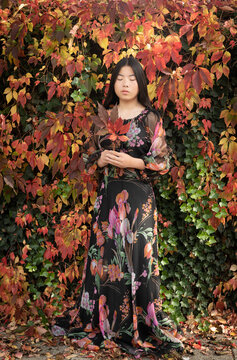 asian girl floral dress hiding in autumn park holding leaves