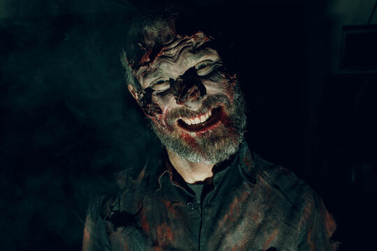 Zombie dead man with blood and old skin on his face walking on halloween party.
