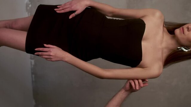 A young guy runs his hand over the shoulder of his girlfriend in a black dress, takes her hand and leads her out of the frame. Relationship concept.