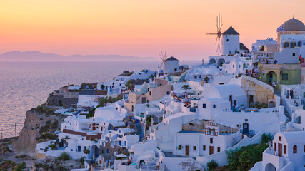 White churches an blue domes by the ocean of Oia Santorini Greece, a traditional Greek village in Santorini during summer at sunset