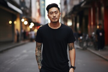 Asian man in a black T-shirt with tattoos in the city