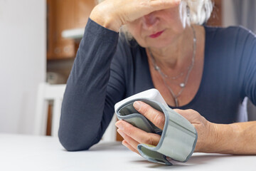 Woman lis looking at the results of blood pressure measurement with her hand on her forehead. © frank11