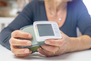 Woman is showing a blood pressure monitor with empty display ready for your text.