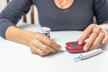 Home health prevention. Woman prepares a blood glucose meter for use, Horizontally.