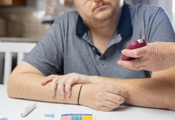 Female hand holds a blood glucose meter and shows the results to a man. Horizontally. 