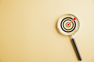 A magnifier glass hones in on a target board, representing the pursuit of business objectives. background and copy space, it symbolizes marketing success, innovation, and charting winning strategy.